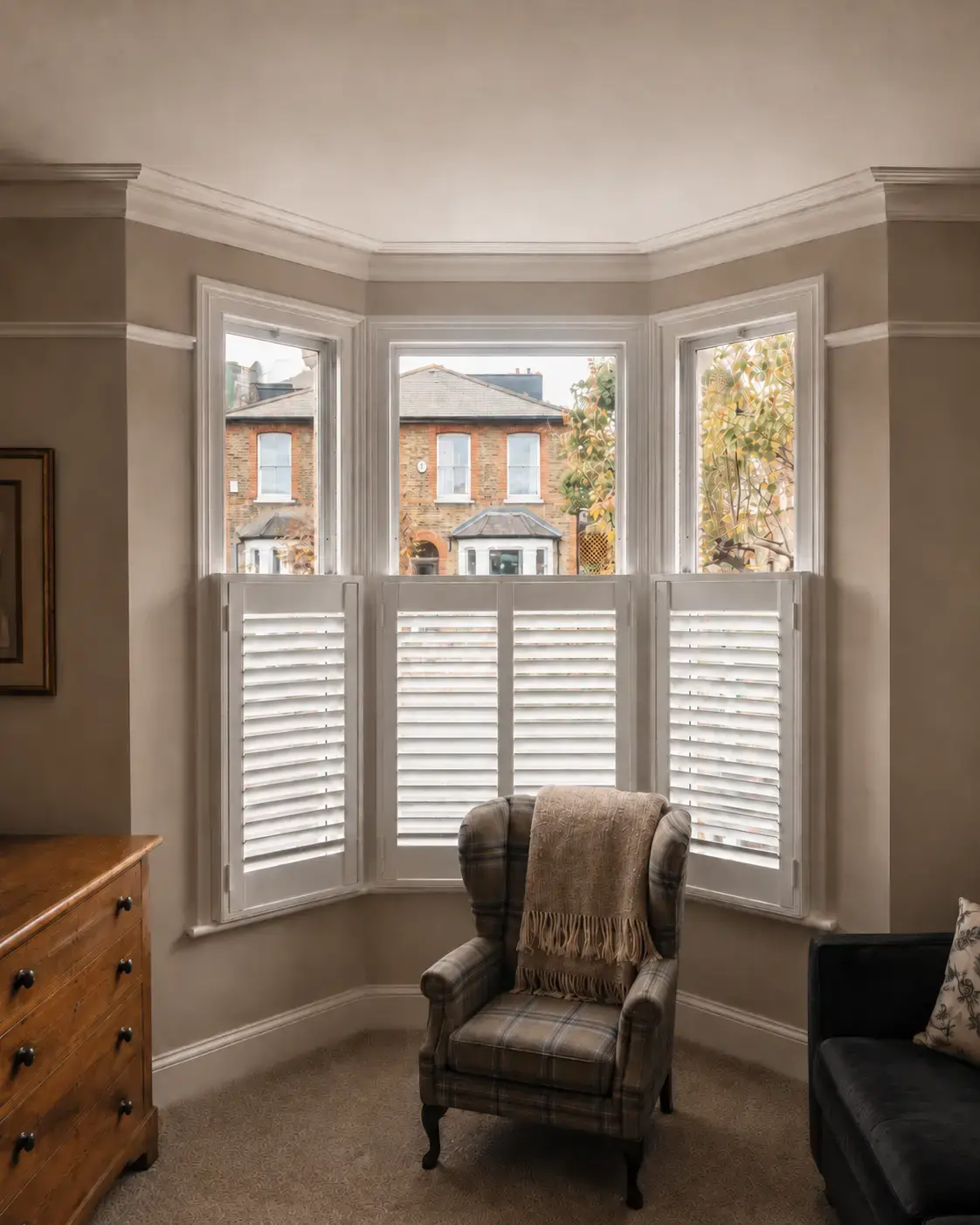 White plantation shutters across the lower sections of a bay window, with the upper glass uncovered